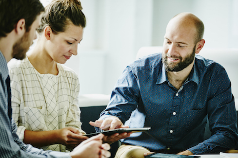 Smiling man pointing to information on a tablet computer.
